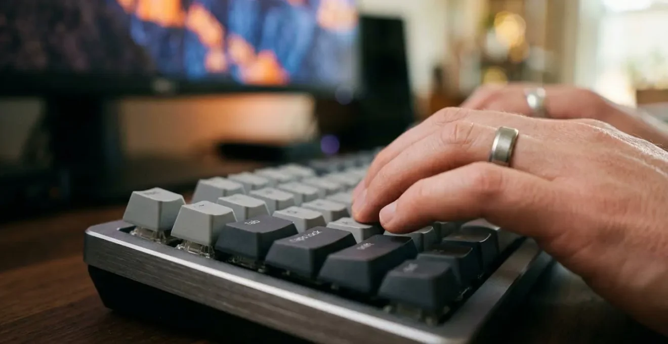 Mains tapant sur clavier avec écran d'ordinateur flou en arrière-plan montrant une interface email