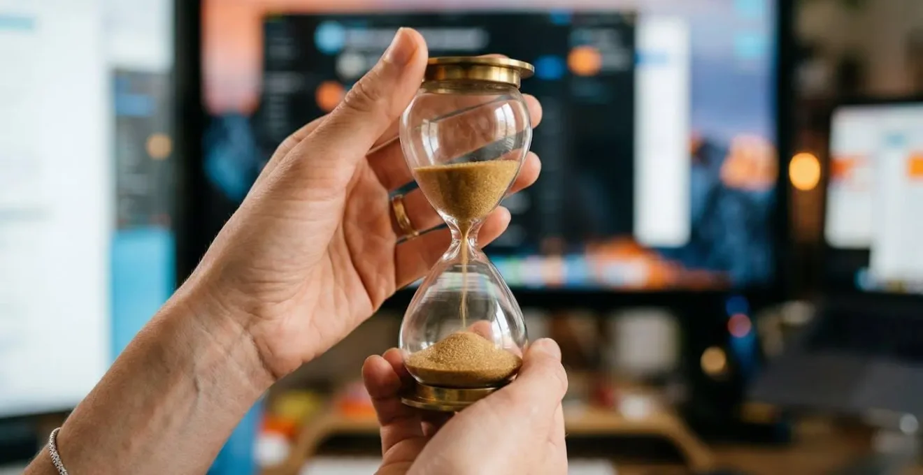 Gros plan sur des mains tenant un sablier avec du sable qui s'écoule rapidement, représentant le temps limité de l'attention utilisateur